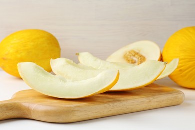 Photo of Whole and cut ripe melons on white table