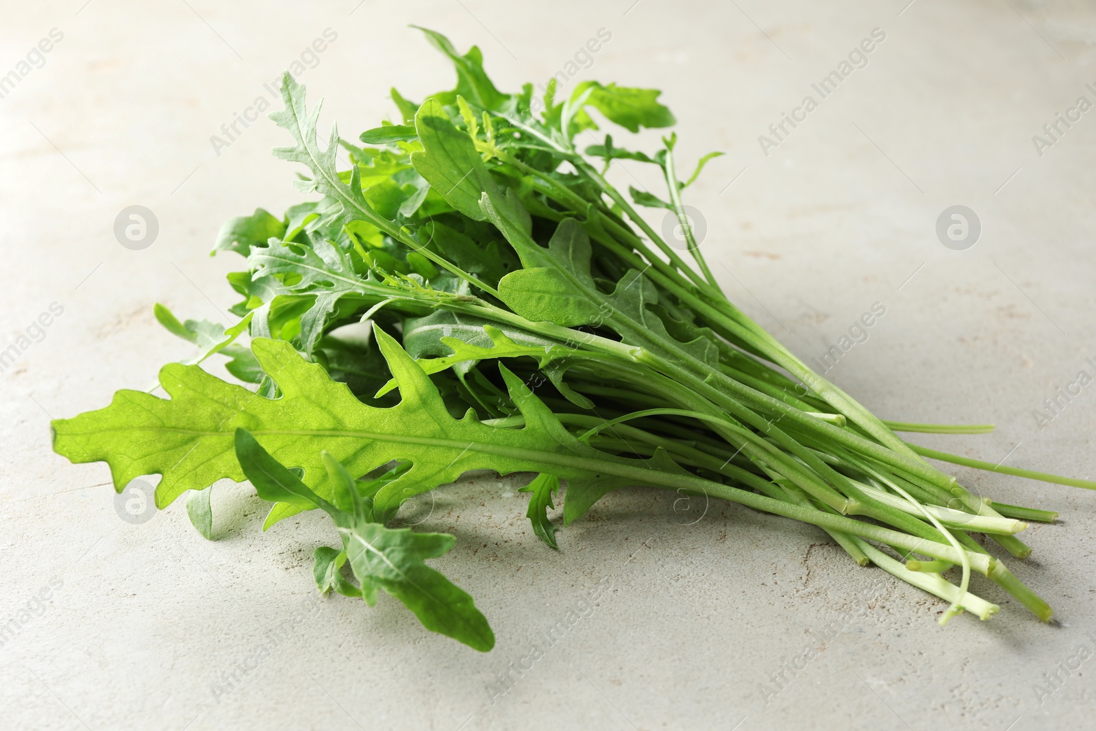 Photo of Many fresh arugula leaves on grey textured table, closeup