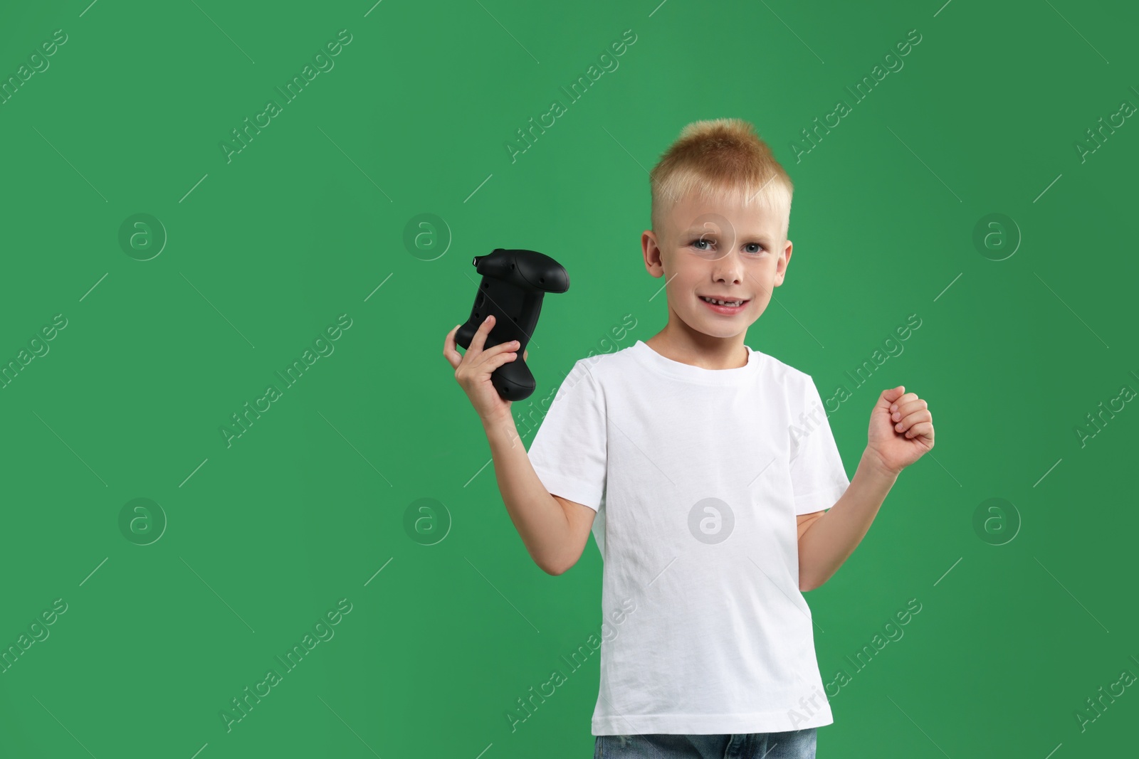 Photo of Happy little boy with controller on green background. Space for text