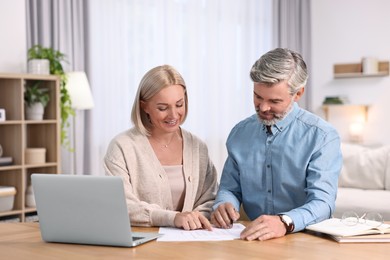 Photo of Happy middle aged couple working at wooden table indoors