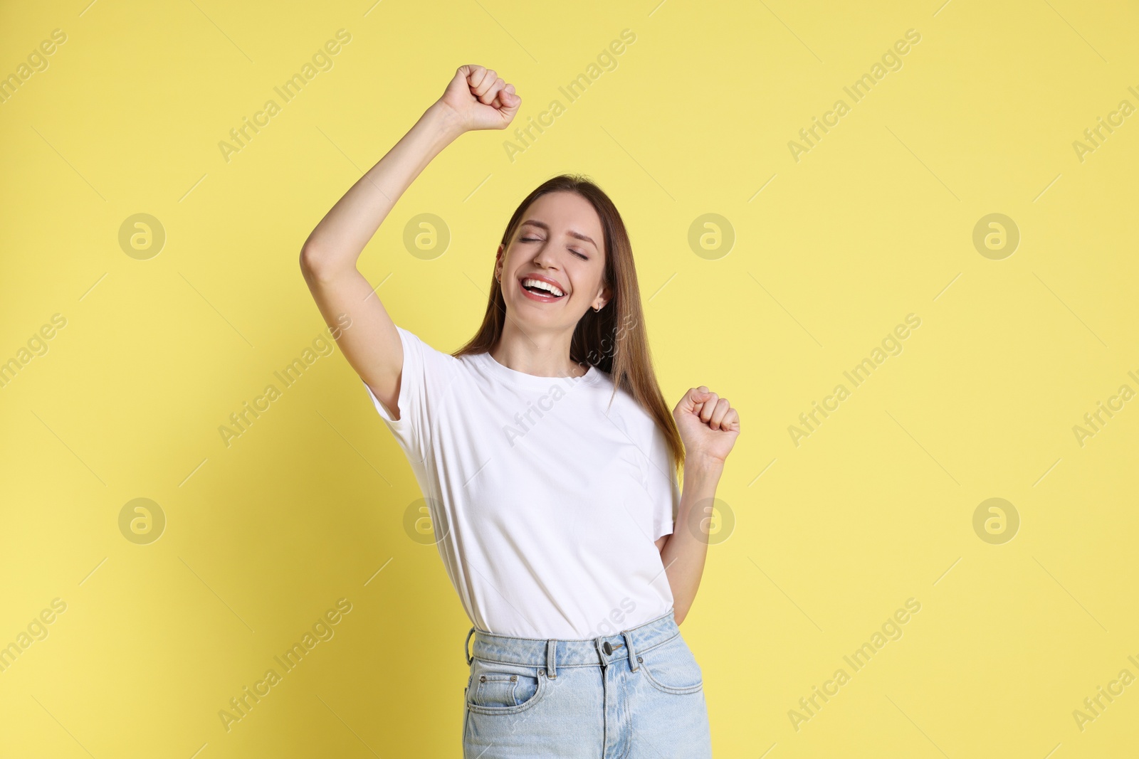 Photo of Portrait of happy winner on yellow background