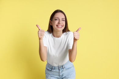 Happy winner showing thumbs up on yellow background