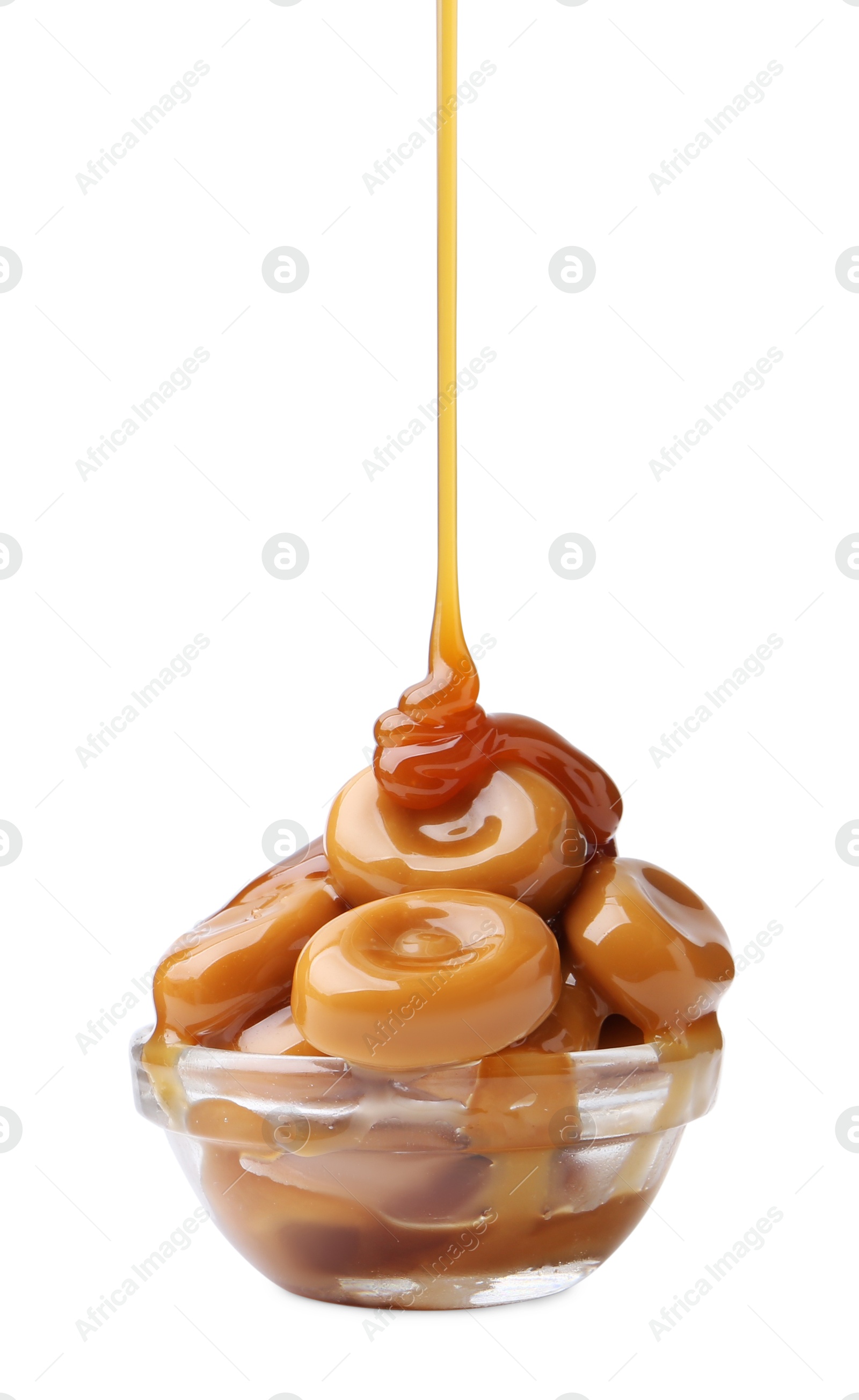 Photo of Caramel sauce dripping onto candies on white background, closeup