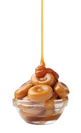 Photo of Caramel sauce dripping onto candies on white background, closeup