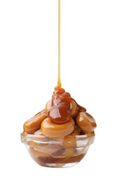 Photo of Caramel sauce dripping onto candies on white background, closeup