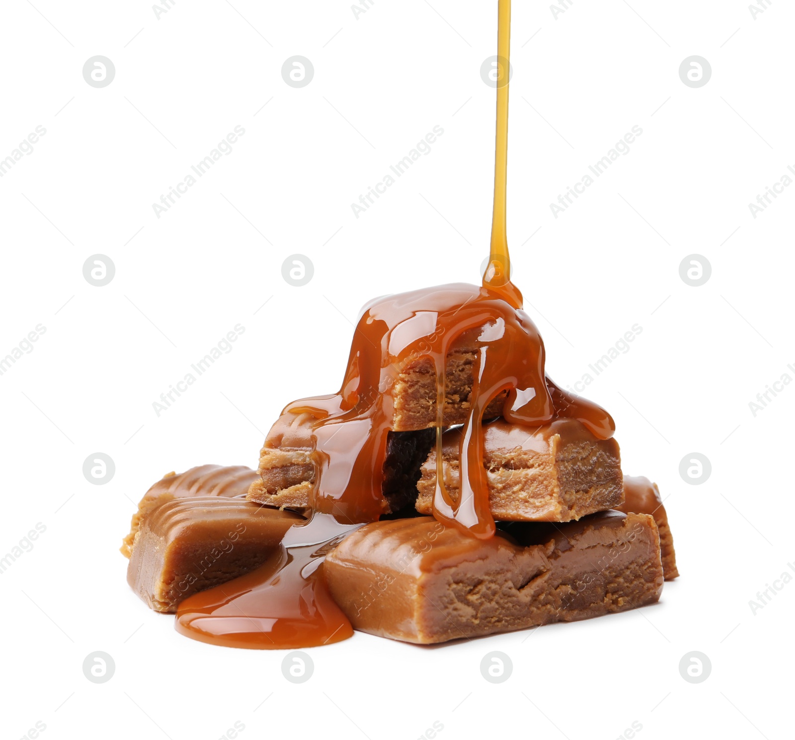 Photo of Caramel sauce dripping onto candies on white background, closeup