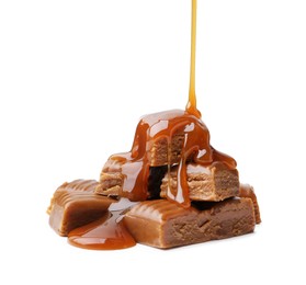 Photo of Caramel sauce dripping onto candies on white background, closeup