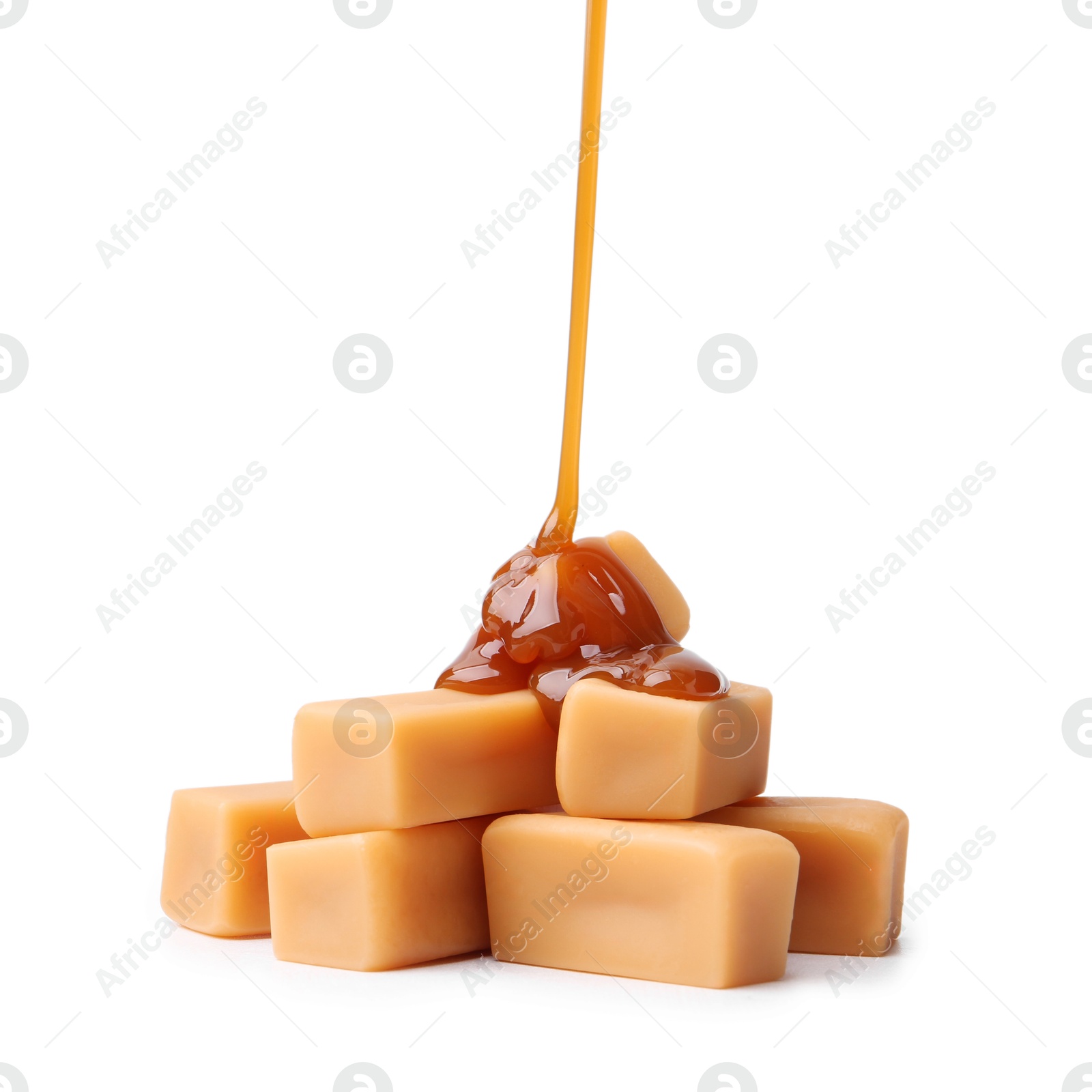 Photo of Caramel sauce dripping onto candies on white background, closeup