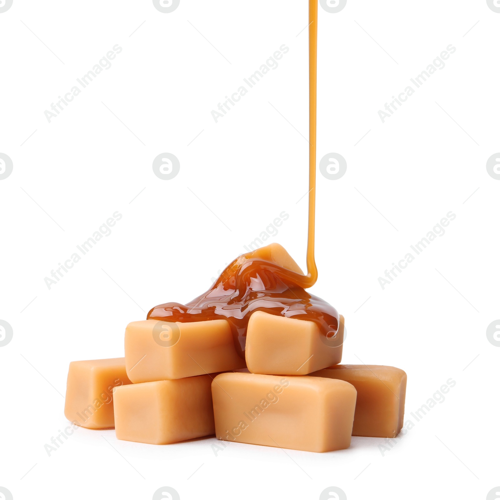 Photo of Caramel sauce dripping onto candies on white background, closeup