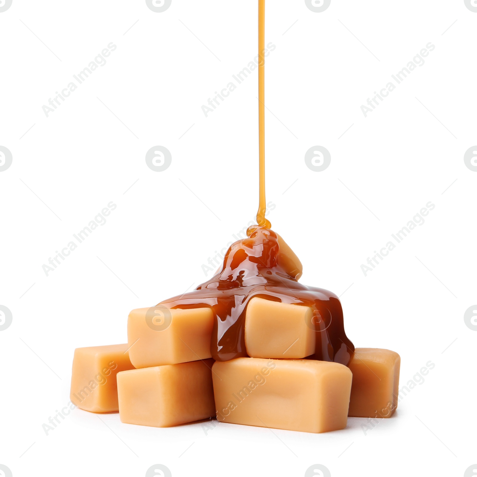 Photo of Caramel sauce dripping onto candies on white background, closeup