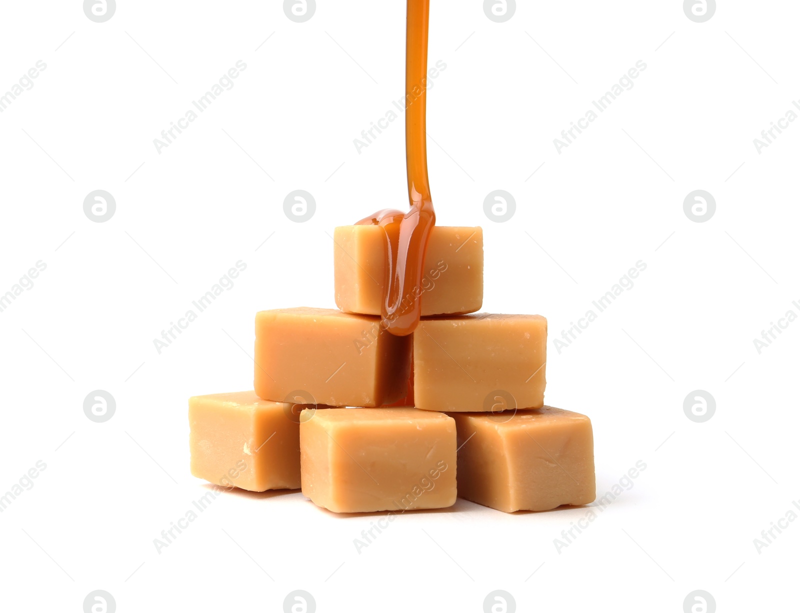 Photo of Caramel sauce dripping onto candies on white background, closeup