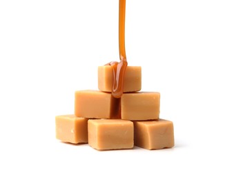 Photo of Caramel sauce dripping onto candies on white background, closeup