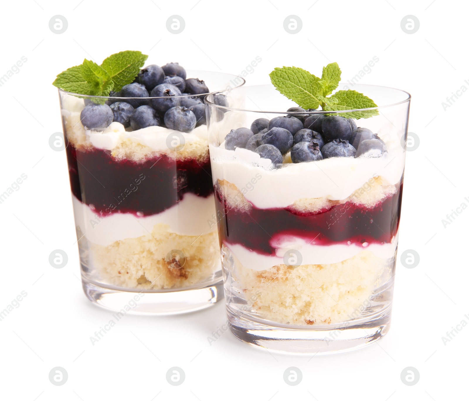 Photo of Tasty trifle dessert. Sponge cake, blueberries, jam and whipped cream in glasses isolated on white