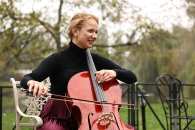 Photo of Beautiful young woman playing cello in park