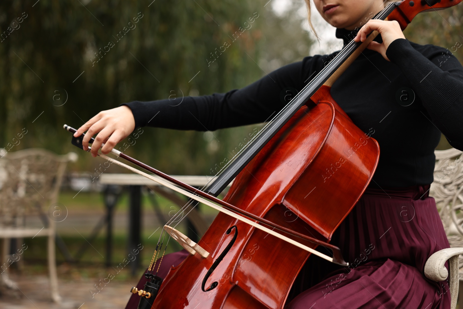 Photo of Young woman playing cello in park, closeup