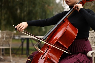 Photo of Young woman playing cello in park, closeup