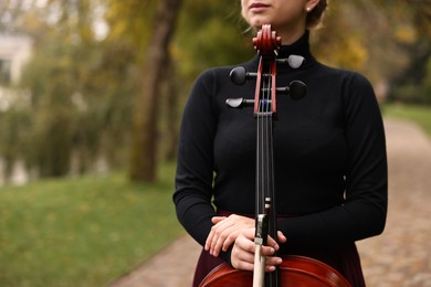 Photo of Young woman with cello in park, closeup