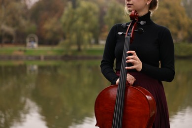 Photo of Young woman with cello in park, closeup. Space for text