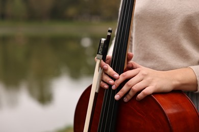 Photo of Young woman with cello in park, closeup. Space for text