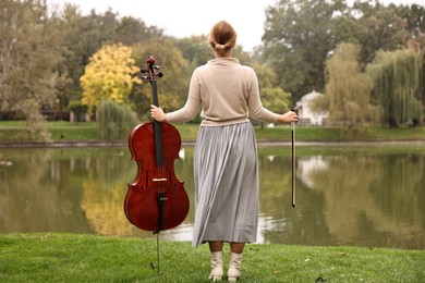 Woman with cello in park, back view