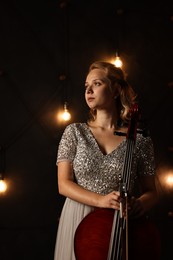 Photo of Beautiful young woman with cello on stage. Classic musical instrument