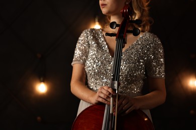 Photo of Young woman with cello on stage, closeup. Classic musical instrument