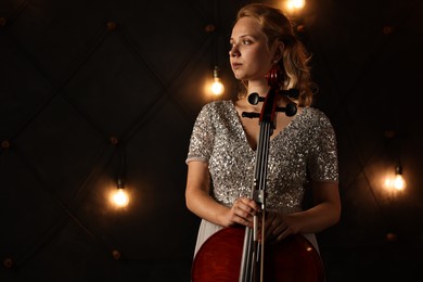 Beautiful young woman with cello on stage, space for text. Classic musical instrument