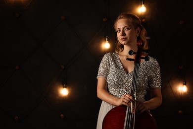 Photo of Beautiful young woman with cello on stage, space for text. Classic musical instrument