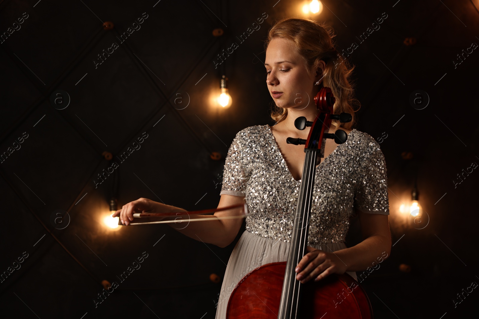 Photo of Beautiful young woman with cello on stage. Classic musical instrument