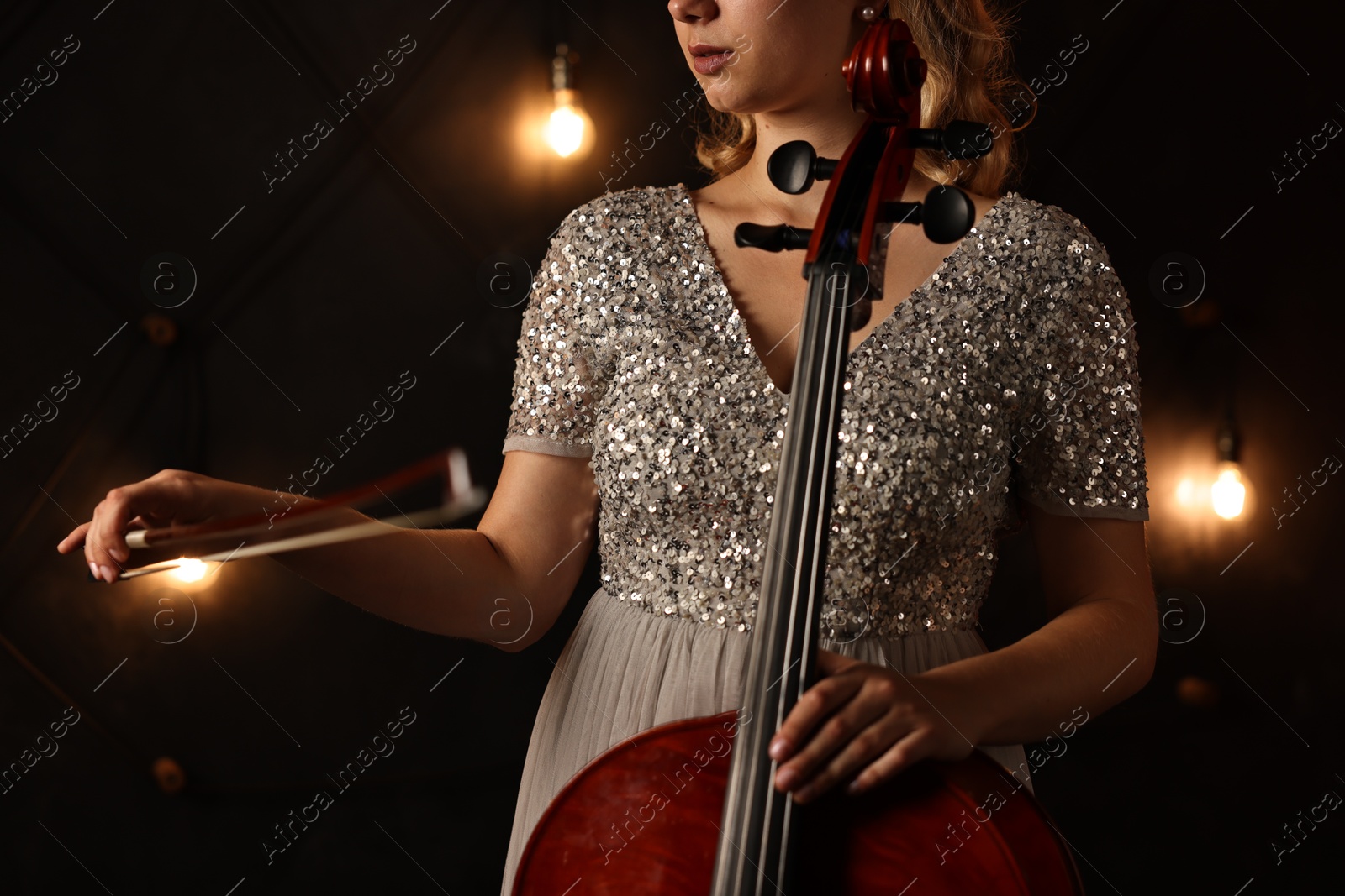 Photo of Young woman with cello on stage, closeup. Classic musical instrument