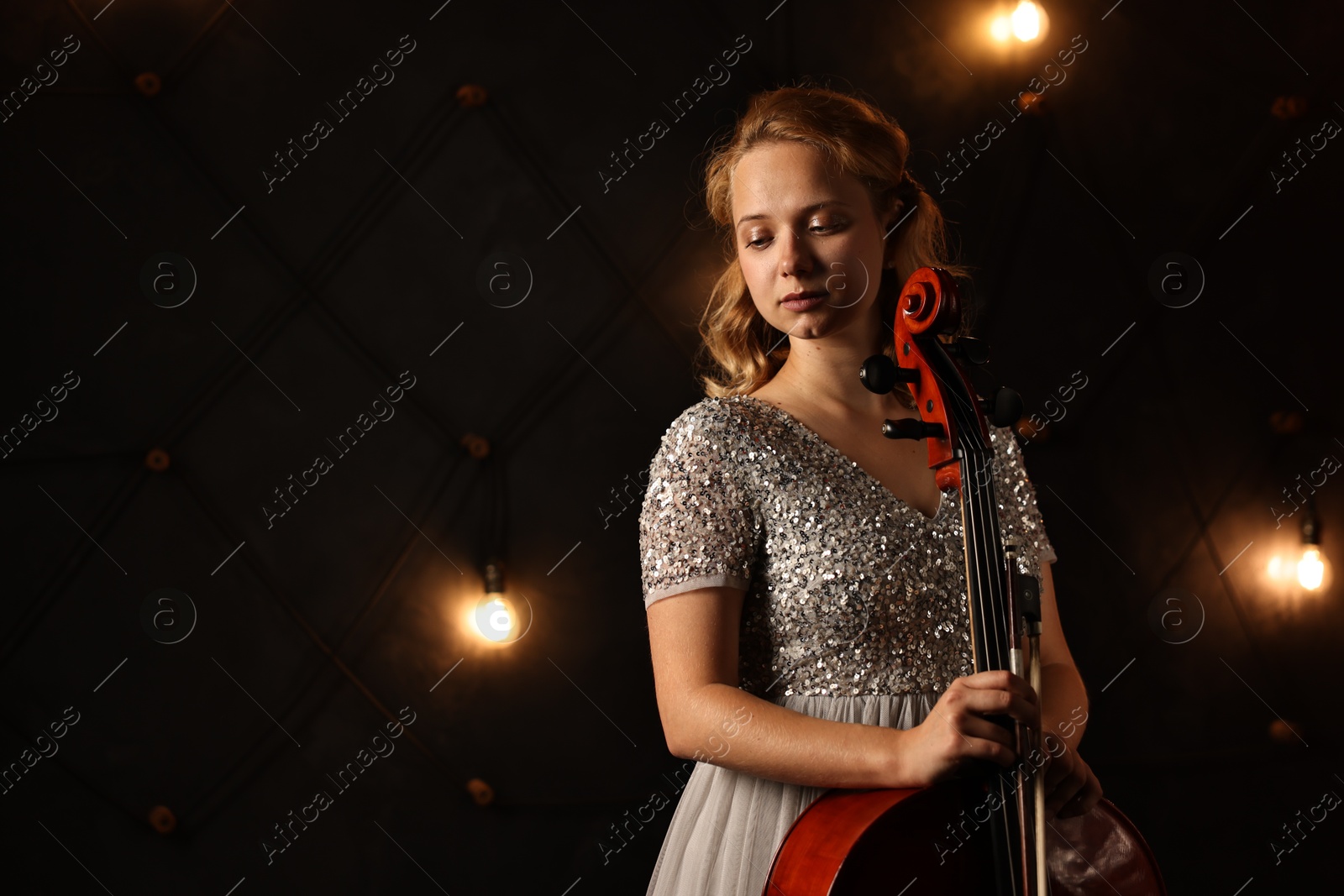 Photo of Beautiful young woman with cello on stage, space for text. Classic musical instrument