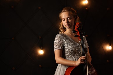 Photo of Beautiful young woman with cello on stage, space for text. Classic musical instrument