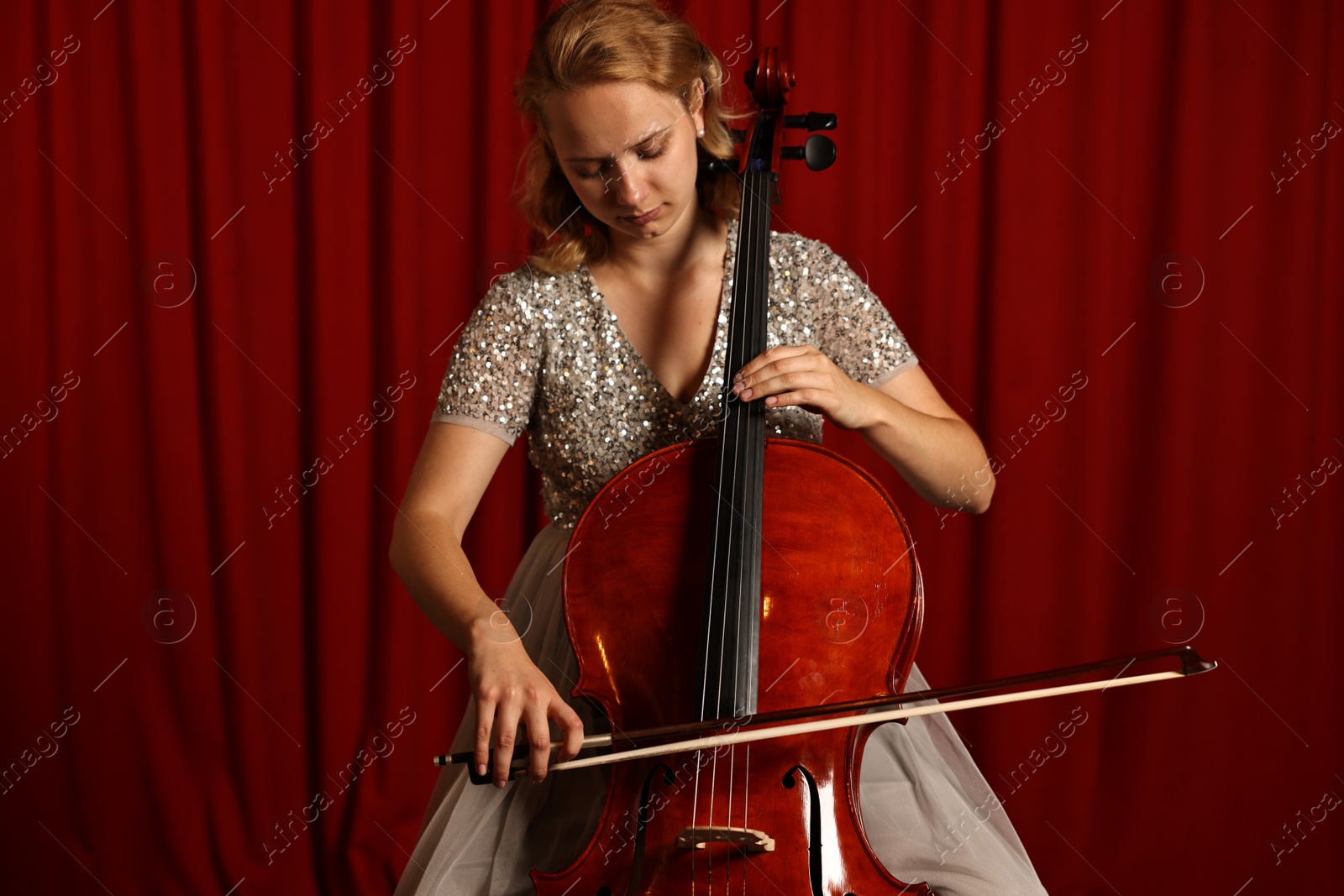 Photo of Beautiful young woman playing cello on stage