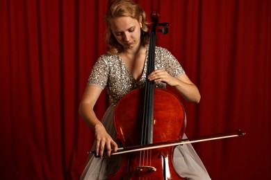 Photo of Beautiful young woman playing cello on stage