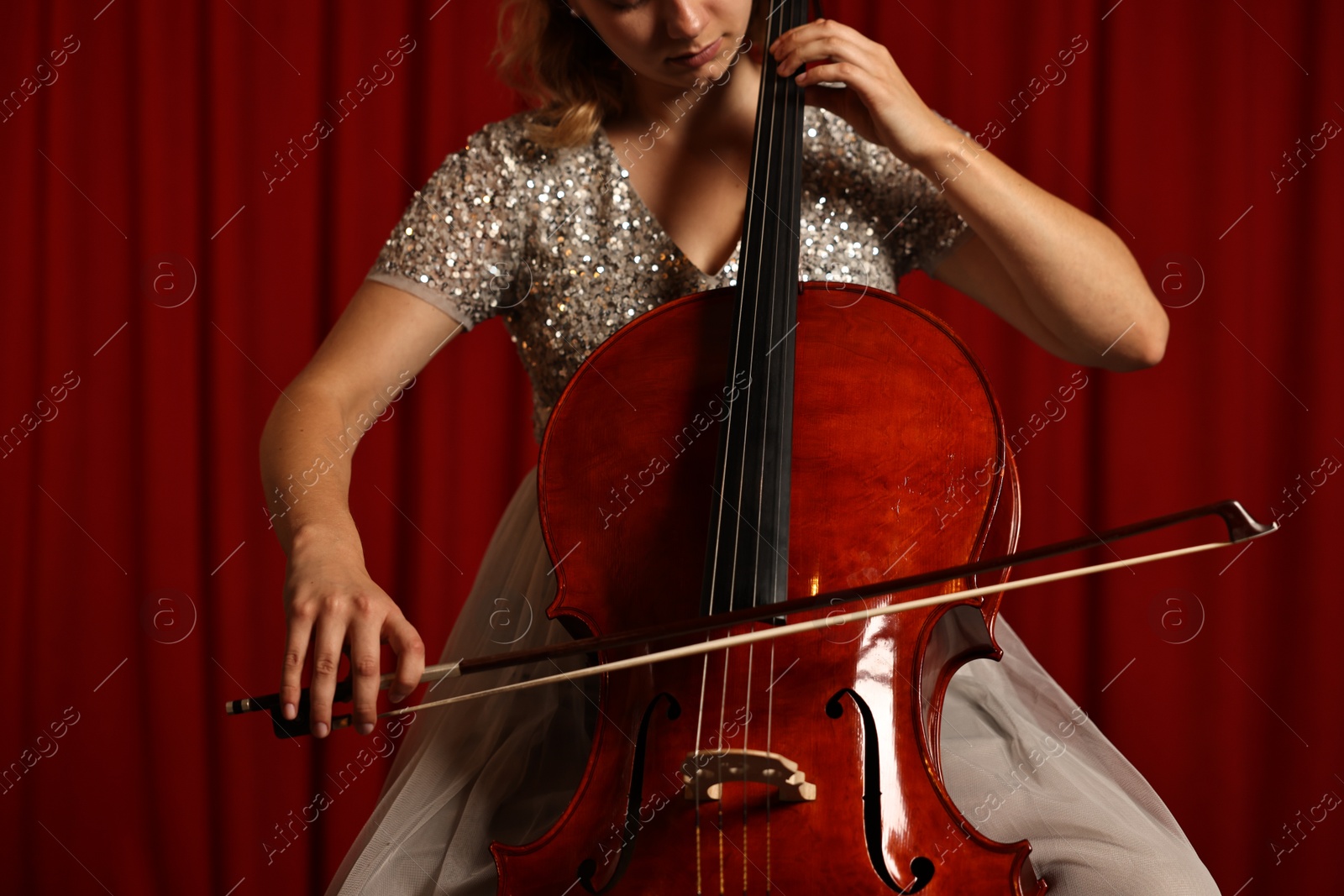 Photo of Young woman playing cello on stage, closeup