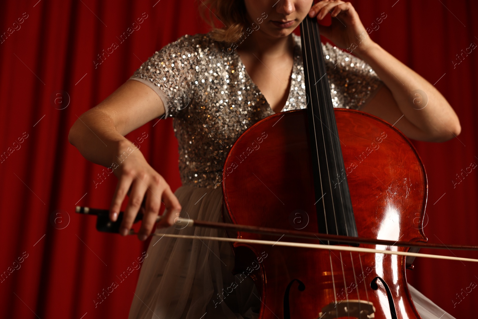 Photo of Young woman playing cello on stage, closeup. Low angle view