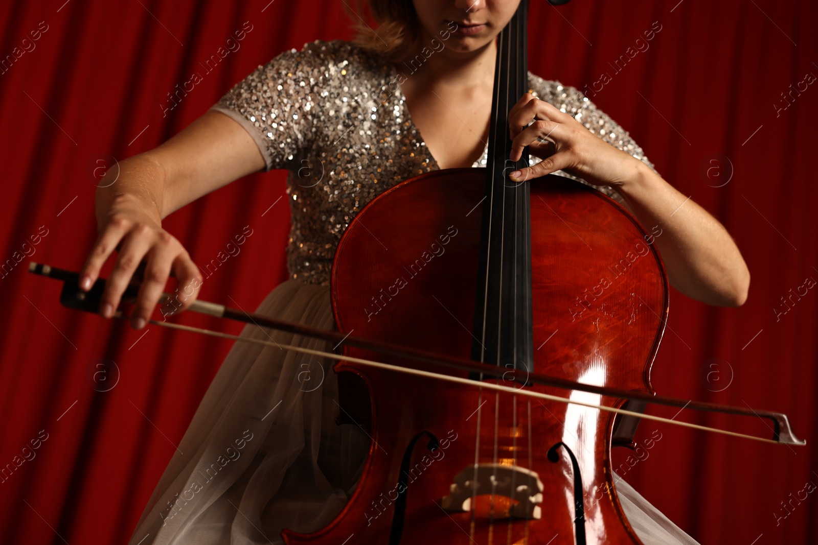 Photo of Young woman playing cello on stage, closeup. Low angle view