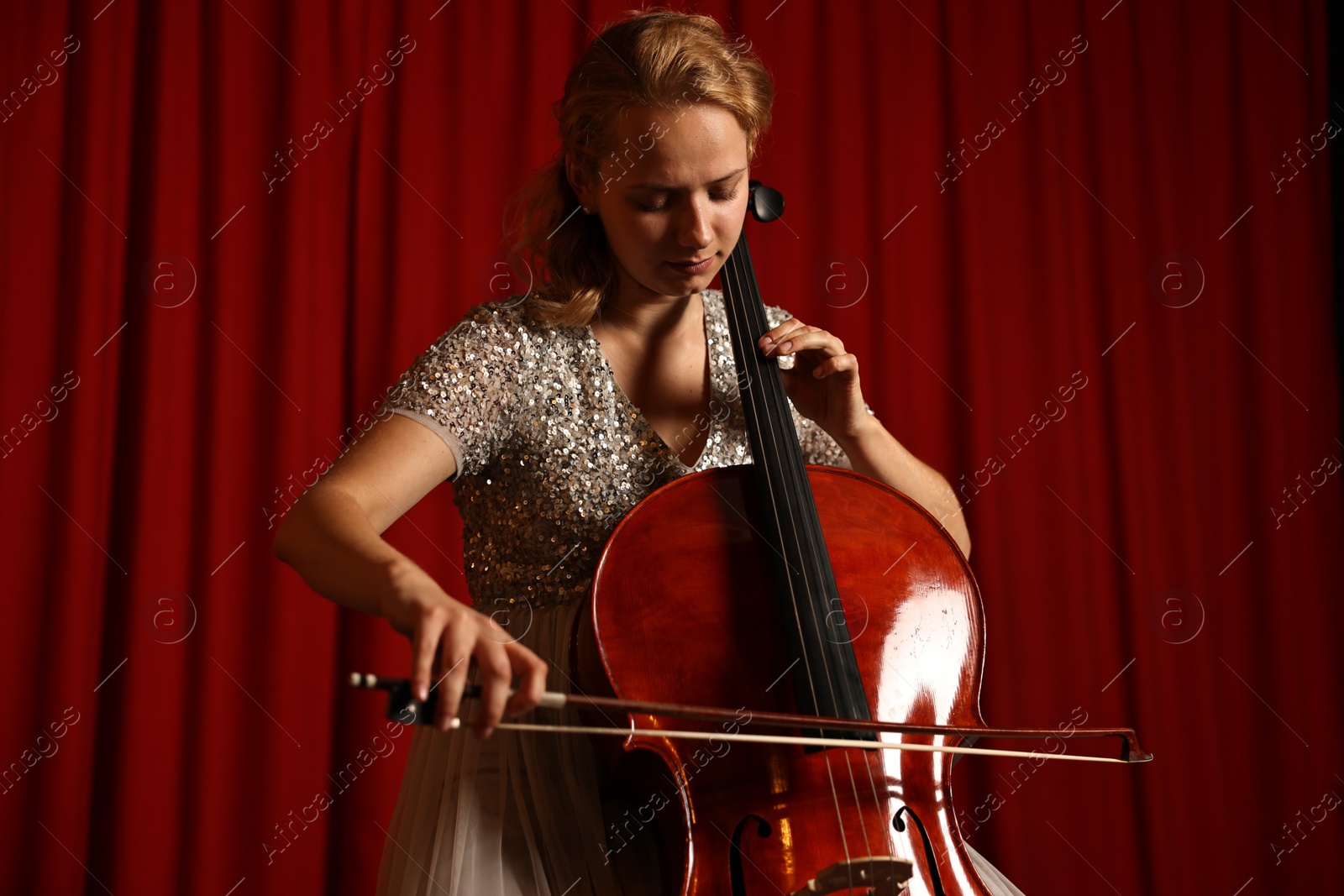 Photo of Beautiful young woman playing cello on stage, low angle view