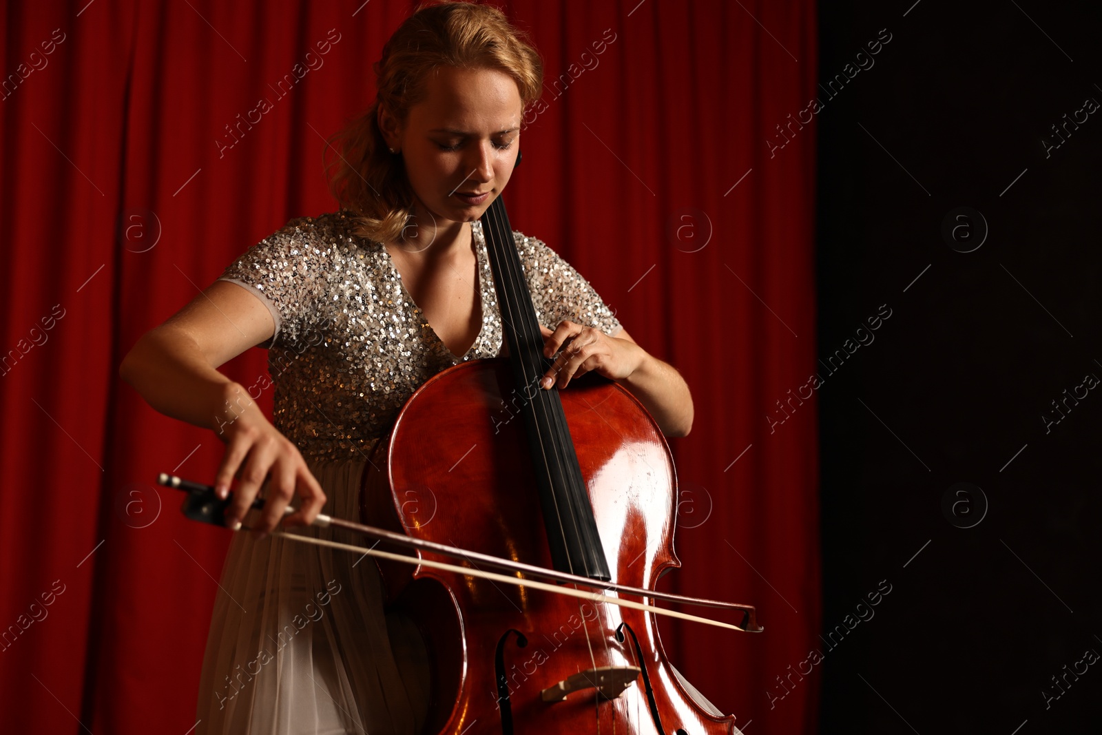 Photo of Beautiful young woman playing cello on stage, space for text