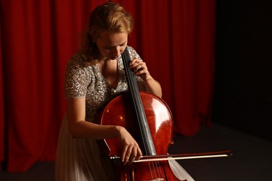 Photo of Beautiful young woman playing cello on stage