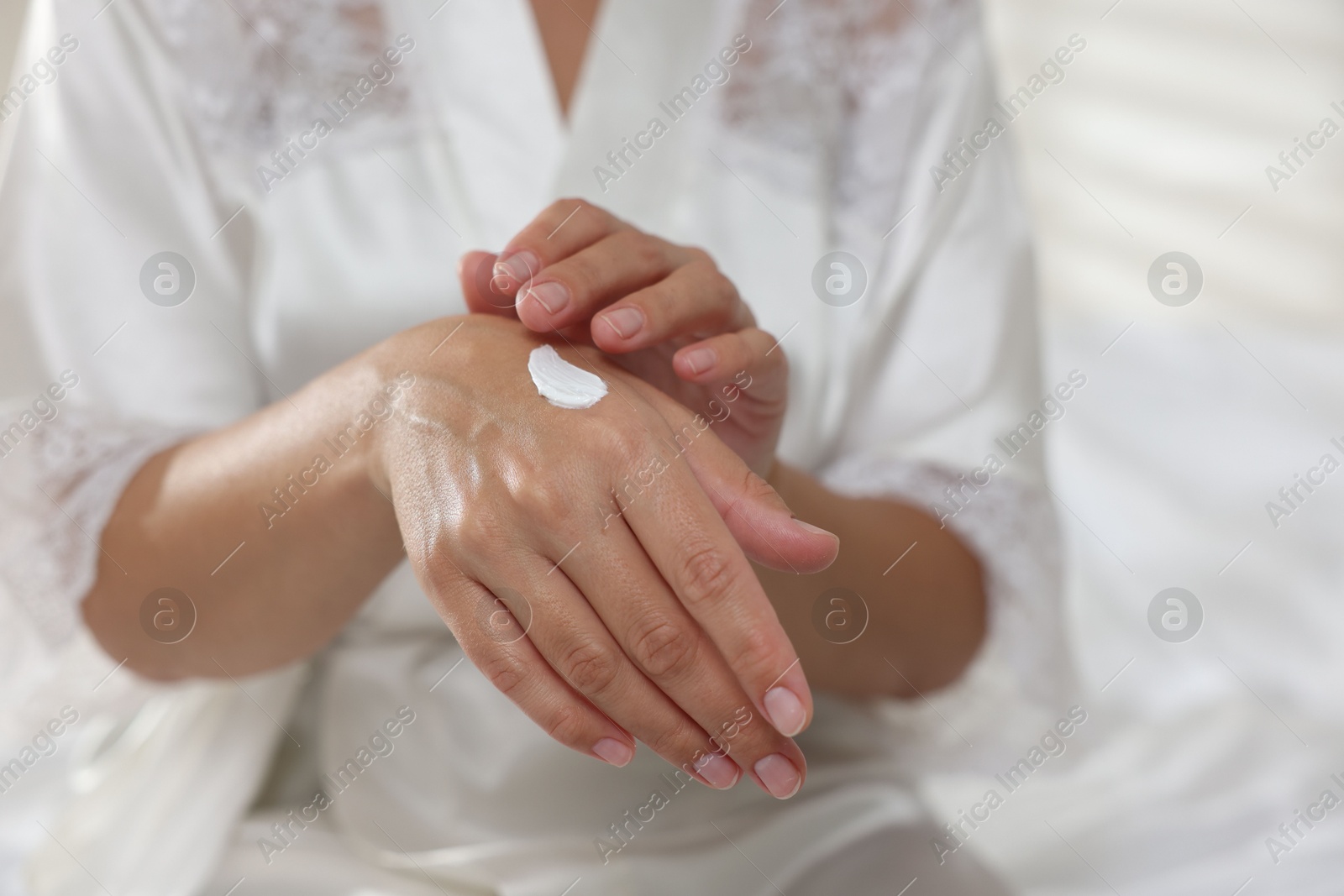 Photo of Woman applying cream onto hand at home, closeup