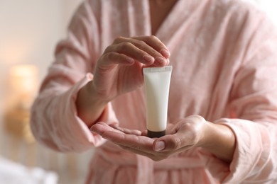 Photo of Woman with tube of cream at home, closeup