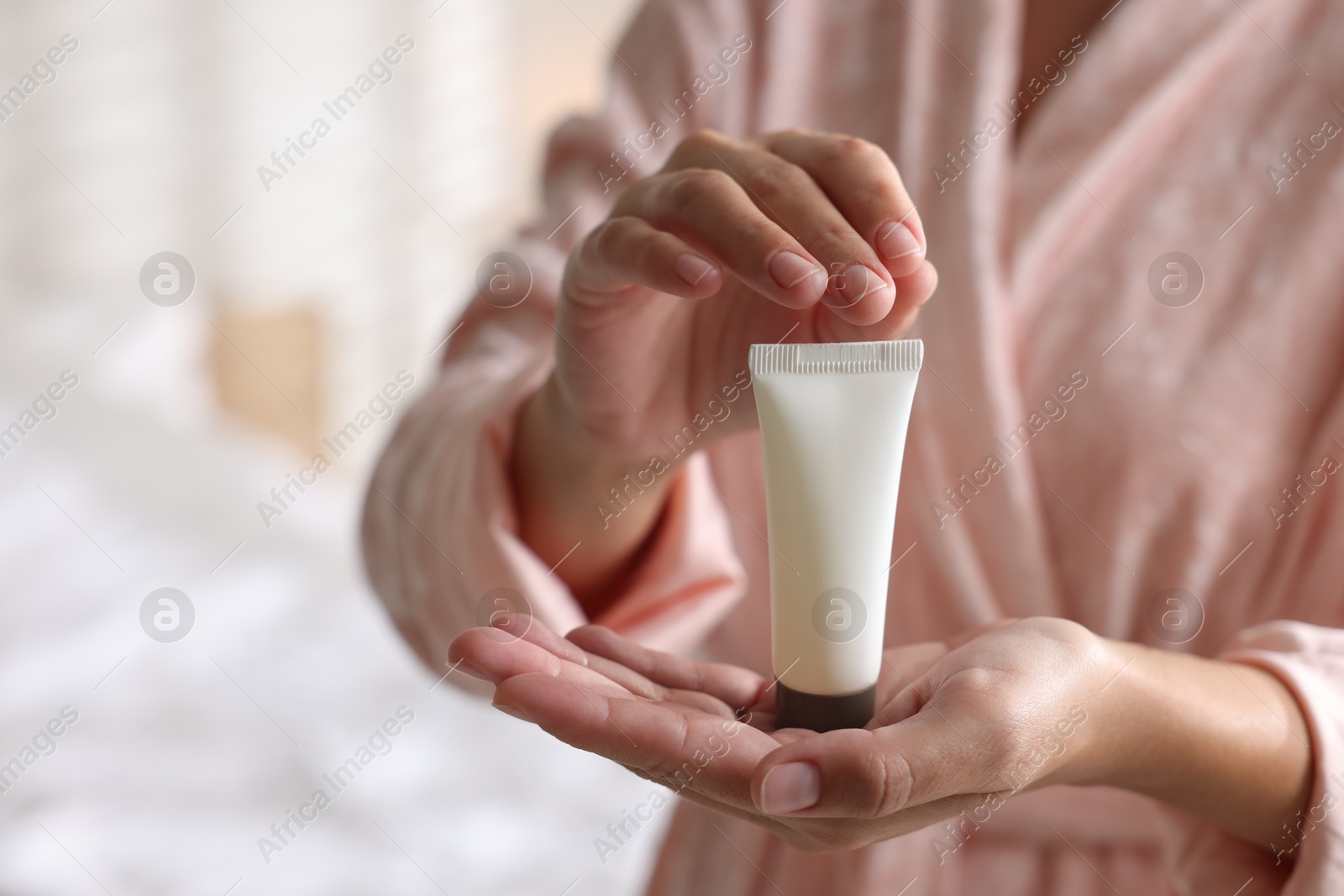 Photo of Woman with tube of cream at home, closeup