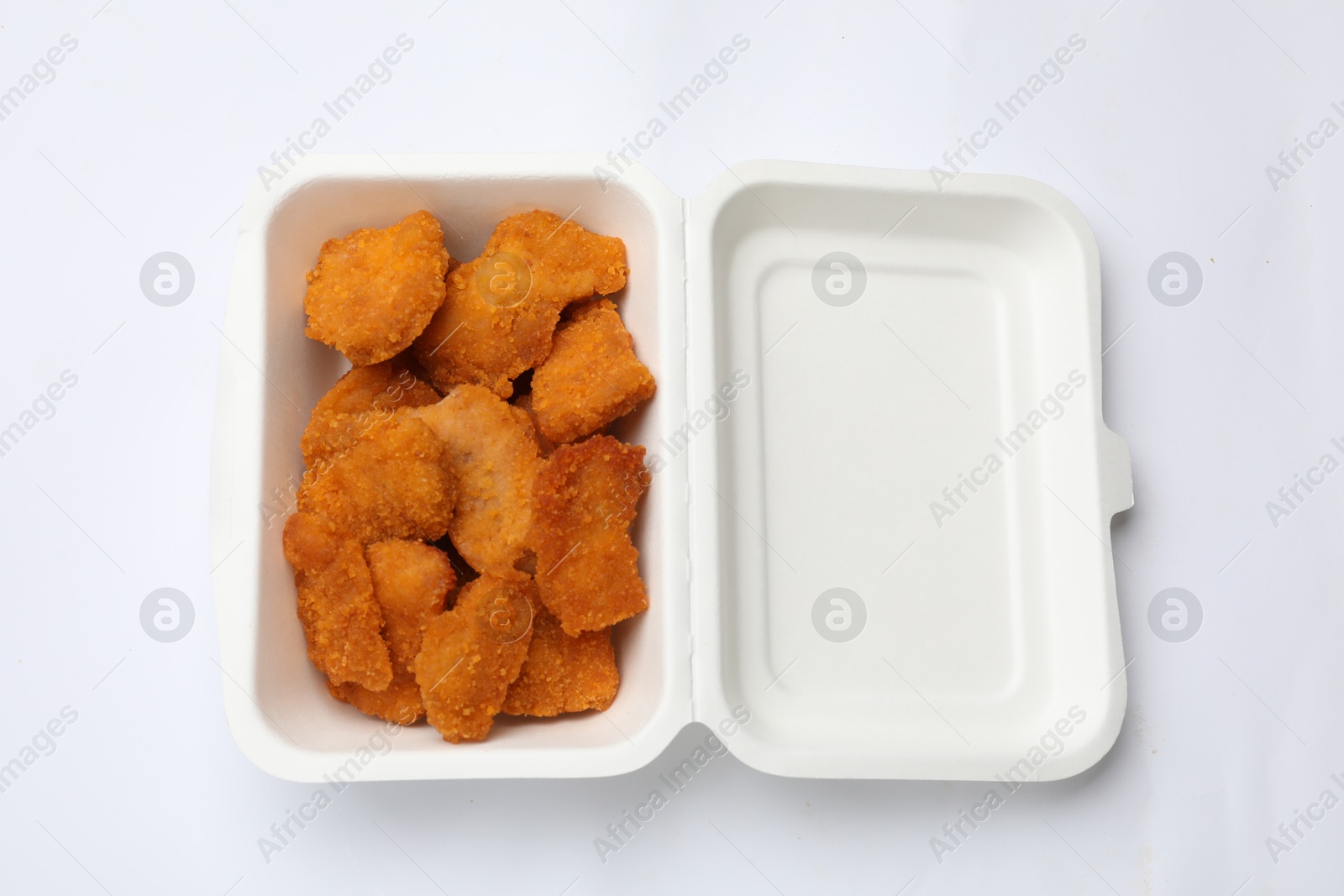 Photo of Delicious chicken nuggets in takeaway container on white background, top view