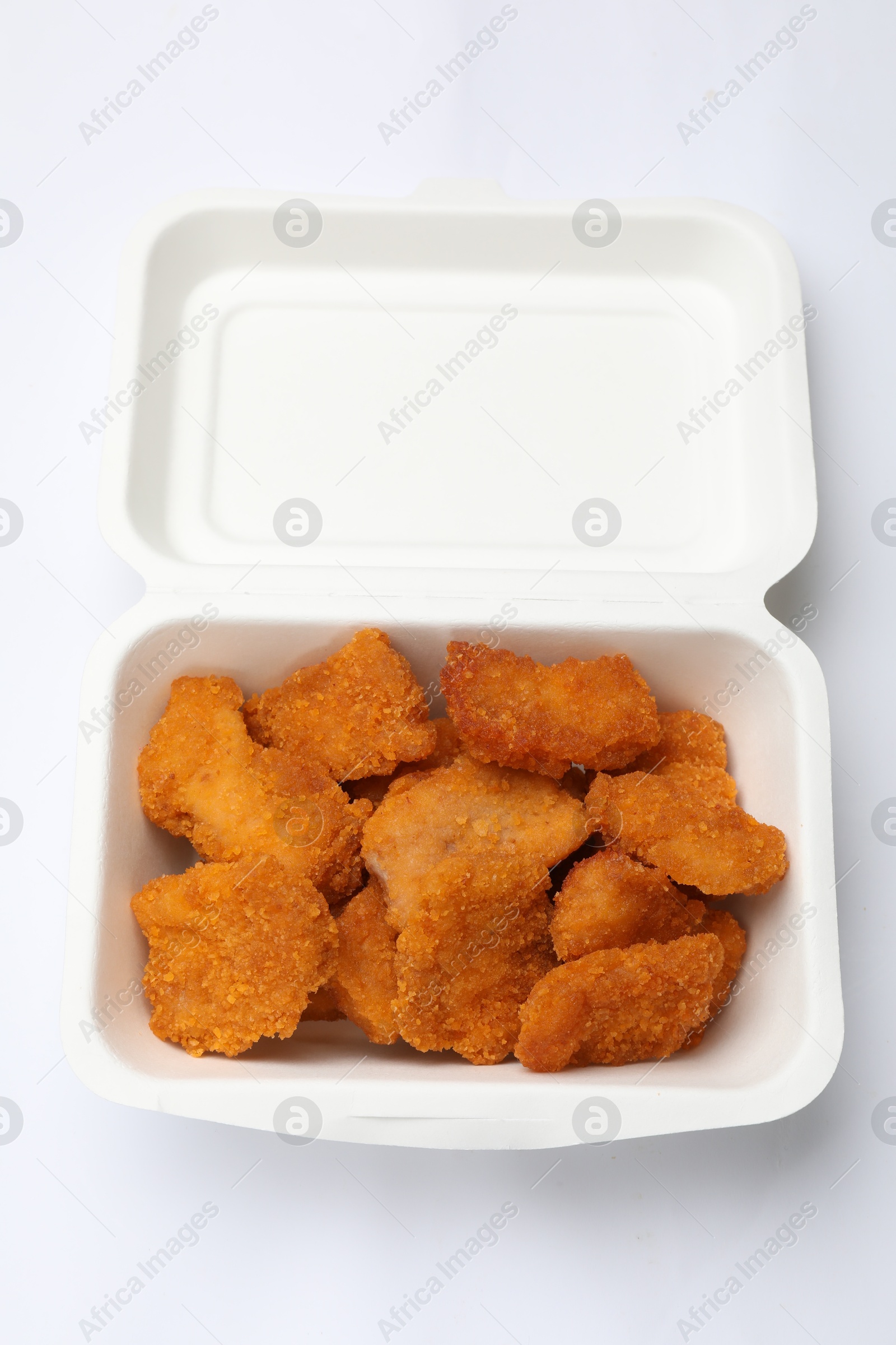 Photo of Delicious chicken nuggets in takeaway container on white background, top view