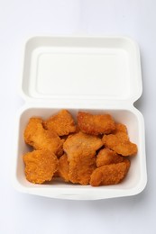 Photo of Delicious chicken nuggets in takeaway container on white background, top view