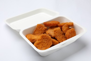 Photo of Delicious chicken nuggets in takeaway container on white background