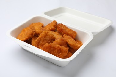 Photo of Delicious chicken nuggets in takeaway container on white background