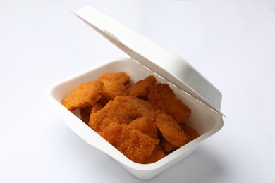 Photo of Delicious chicken nuggets in takeaway container on white background