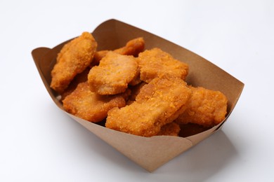 Photo of Delicious chicken nuggets in carton box on white background